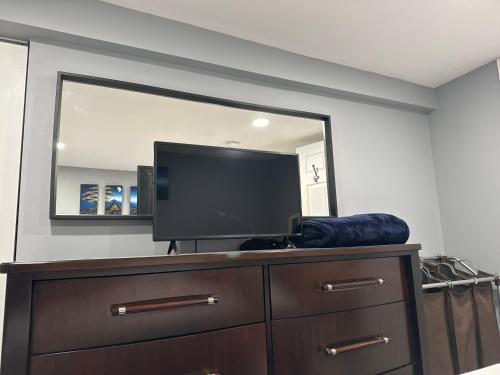 a flat screen tv on a dresser in front of a mirror at Cozy Finished Garden Level Bed+Bath in Dedham
