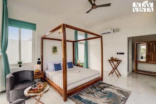 a bedroom with a canopy bed and a chair at StayVista's Kundan Villa - Pet-Friendly Villa with Sprawling Lawn, Outdoor Pool in Jaipur