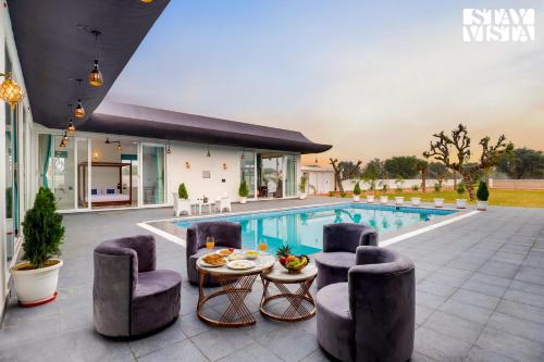 a villa with a pool and a table and chairs at StayVista's Kundan Villa - Pet-Friendly Villa with Sprawling Lawn, Outdoor Pool in Jaipur