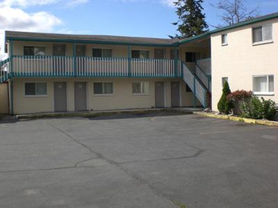 ein Apartmenthaus mit einem Parkplatz davor in der Unterkunft Shamrock Motel in Bellingham