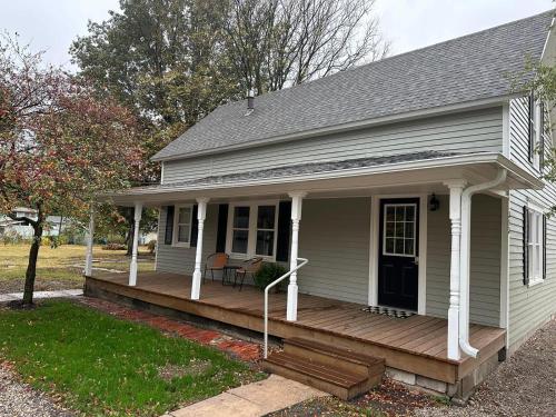 a small white house with a wooden porch at Crabapple Cottage in Hesston