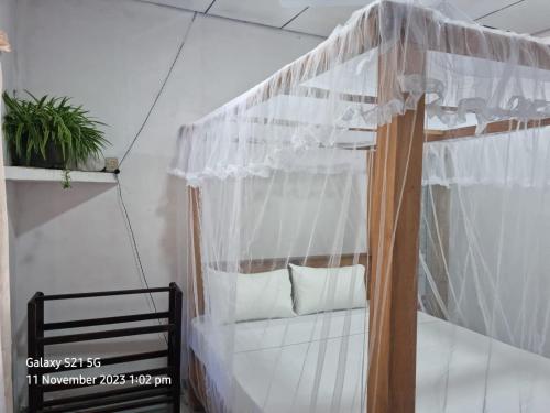 a bedroom with a canopy bed with white curtains at Koala Homestay in Weligama
