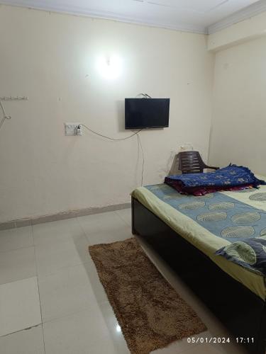 1 dormitorio con 1 cama y TV en la pared en Hobbit, en Gurgaon