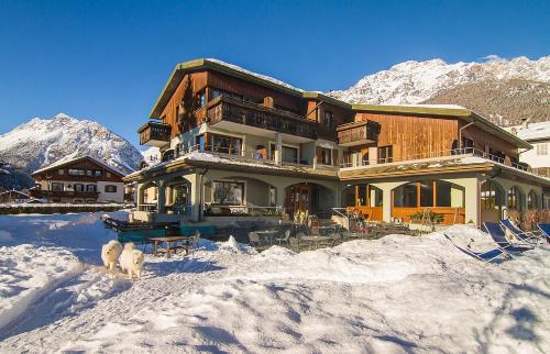 a house in the snow with a dog in front of it at Hotel Nevada in Bormio