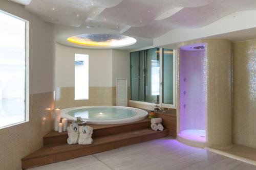 un ampio bagno con vasca e grande specchio di Grand Hotel Da Vinci a Cesenatico