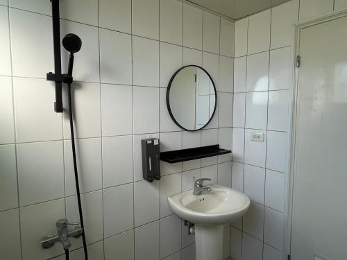 a white tiled bathroom with a sink and a mirror at 埔里北梅民宿BEI MEI Homestay可包棟 in Puli