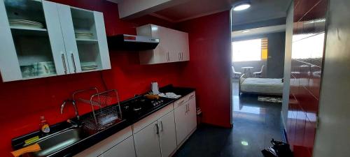 uma cozinha com paredes vermelhas, armários brancos e um lavatório. em Departamento a pasos de la playa em Iquique