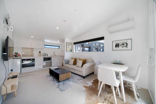a white living room with a couch and a table at Blackrock Apartments Queenstown in Queenstown