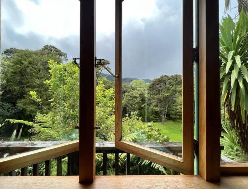 a window view of a forest from a balcony at Forest Hideaway ~ Rustic in Coromandel Town