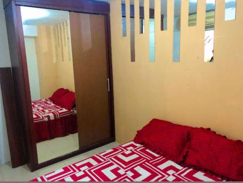 a bedroom with a mirror and a bed with red sheets at Apartemen Kalibata City By Diamond Property in Jakarta
