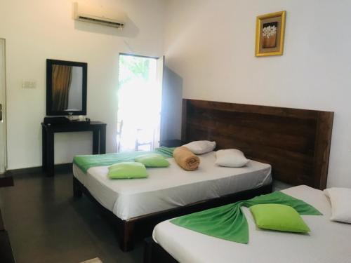 a bedroom with two beds with green and white pillows at Polonnaruwa Holiday Inn in Polonnaruwa