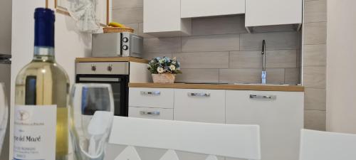 a kitchen with white cabinets and a bottle of wine at Aedes Residenza Lido - 80 mt dalla spiaggia - self check-in in Alghero