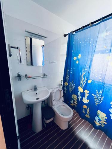 a bathroom with a sink and a toilet and a shower curtain at Avocado Accommodations in Khadkagaon