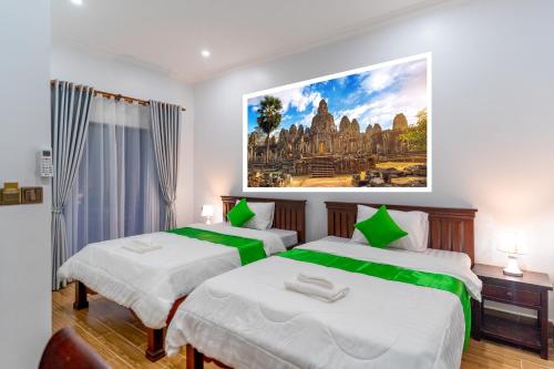 two beds in a room with a painting on the wall at The Khmer house Villas in Siem Reap