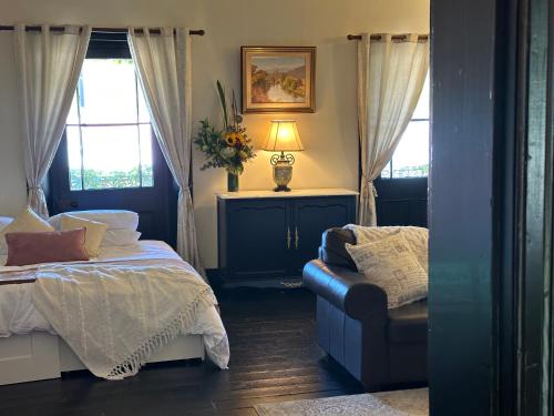 a bedroom with a bed and a chair and windows at The Boston Ivy 1880 - The Residence in Mittagong