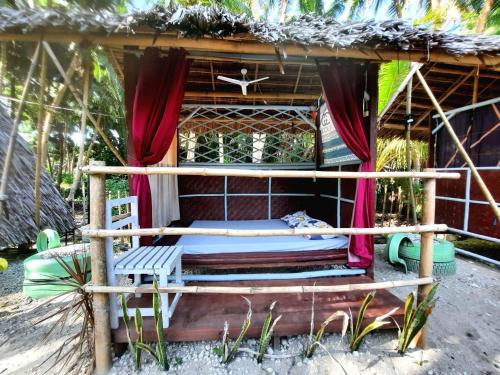 a bed in front of a hut with a window at Destiny Rainbow Beach Resort in Siquijor
