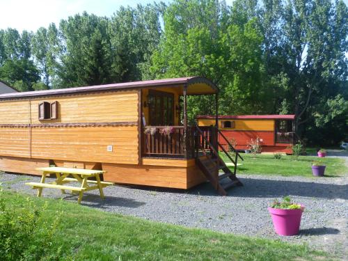 une maison en bois avec une balançoire et une table de pique-nique dans l'établissement Comme Sur Des Roulottes, à Saint-Nectaire
