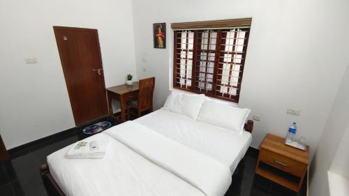 a bedroom with a white bed and a window at SARAS HOME ALAPPUZHA BEACH in Alleppey