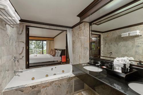 een badkamer met 2 wastafels, een bad en een grote spiegel bij The Front Village - SHA Plus in Karon Beach