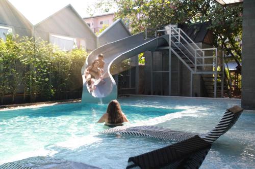 a woman sitting on a chair in a swimming pool at BOOK Design Hotel in Chiang Mai