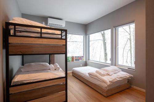 a bedroom with two bunk beds and a window at Moraine Onsen Chalet in Niseko