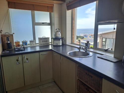 een keuken met een wastafel en een aanrecht met ramen bij Captains View in Jeffreys Bay