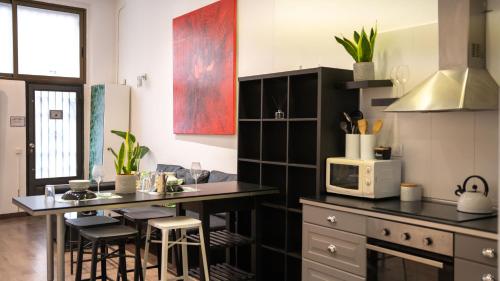 a kitchen with black cabinets and a counter with a microwave at apartment next to park guell in Barcelona