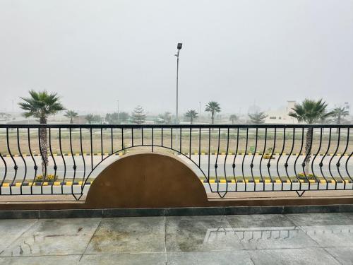a bench with a bridge with palm trees in the background at AS Plaza in Gujrānwāla
