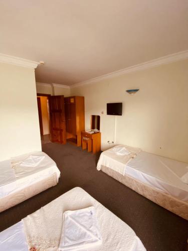a hotel room with three beds and a television at SANCAK HOTEL in Buyukcekmece