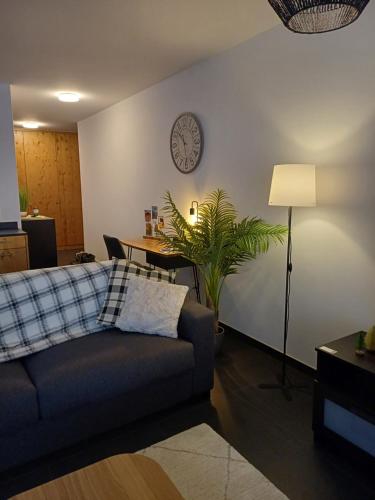 a living room with a couch and a clock on the wall at Spacieux appart - 2 chambres à coucher incl Jacuzzi Privé in Leukerbad