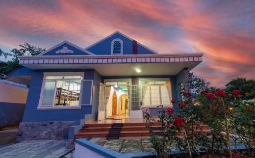 a blue house with a cloudy sky in the background at Trà My Villa Đà Lạt BBQ Garden in Da Lat