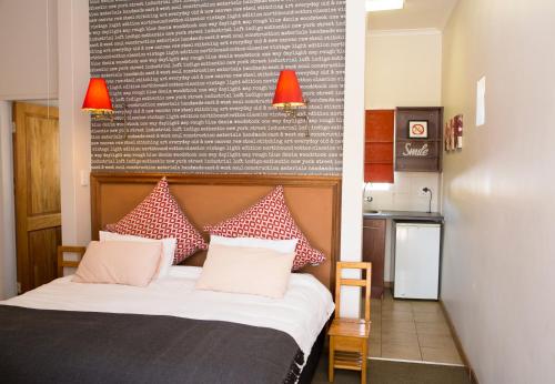 a bedroom with a bed with red and white pillows at Ons Dorpshuis Guesthouse in Rustenburg