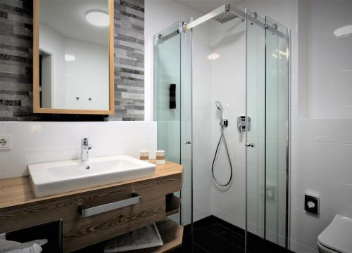 ein Bad mit einem Waschbecken und einer Glasdusche in der Unterkunft Privat & Boutique Hotel Plauer See in Funfseen