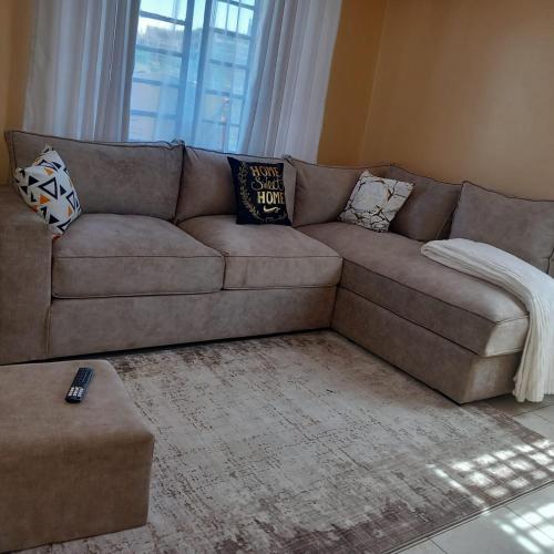 - un canapé brun dans le salon avec des oreillers dans l'établissement Pearl apartment roysambu one bedroom, à Nairobi