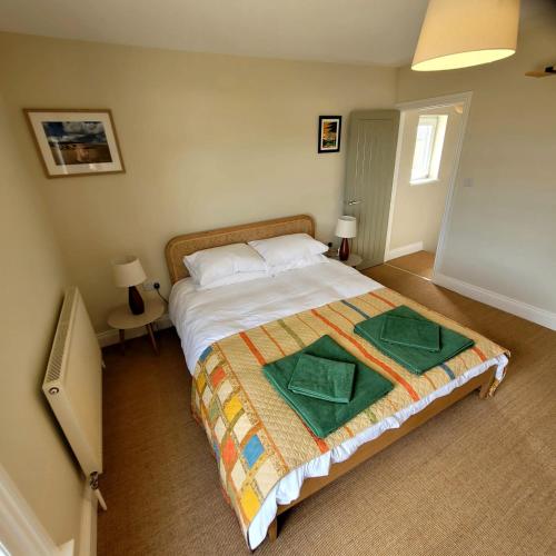 a bedroom with a bed with two green towels on it at Pea Cottage in Kessingland