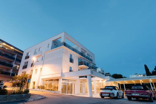 um edifício branco com carros estacionados em frente em Hotel Fanat em Split