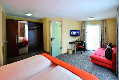 a hotel room with a bed and a red couch at Lindenberger Hof in Lindenberg im Allgäu