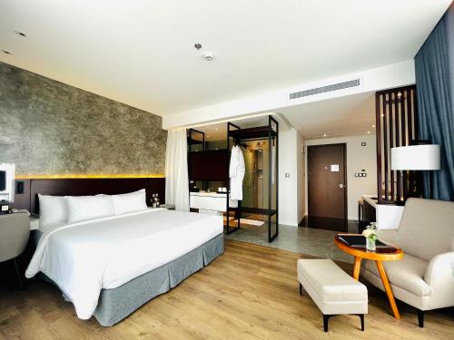 クアンガイにあるNEWCC HOTEL AND SERVICED APARTMENTのベッドルーム(大きな白いベッド1台付)、リビングルームが備わります。