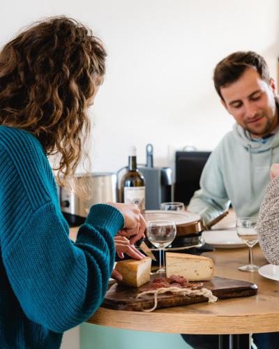 a woman is making a sandwich at a table with wine glasses at Le Patio - Vallée d'Aspe in Bedous