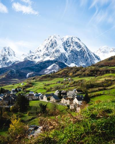 a village in a valley with a snow covered mountain at Le Patio - Vallée d'Aspe in Bedous
