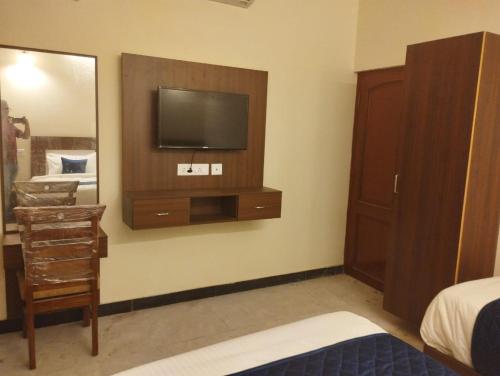 una camera da letto con TV, cassettiera e specchio di A.R Residency a Chennai