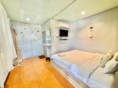 บ้านพักหมอบิวรีสอร์ท في تشيانغ خان: غرفة نوم صغيرة بها سرير وتلفزيون