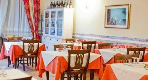 ミラノにあるVilla Lia Depandance Hotel Siciliaのダイニングルーム(テーブル、椅子、オレンジ色のテーブルクロス付)