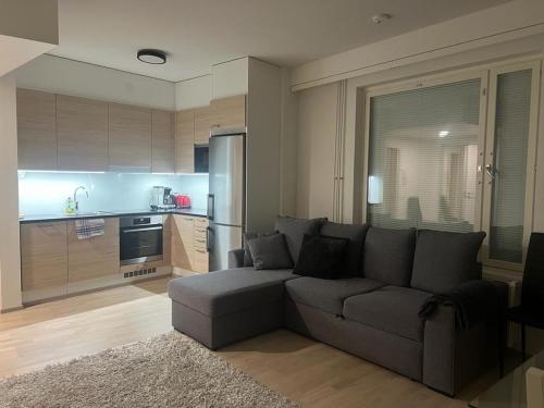 a living room with a couch and a kitchen at Modern city apartment with Sauna nearby the Airport in Vantaa