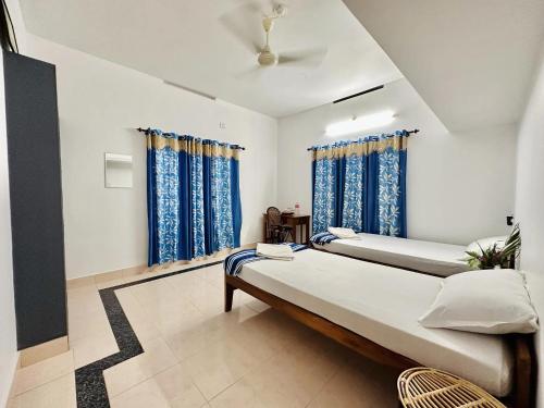 Cette chambre comprend 2 lits et des rideaux bleus. dans l'établissement Varkala Villa, à Varkala