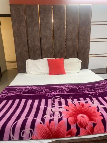 un letto con una coperta viola e un cuscino rosso di Hotel Jyoti Deluxe a Nuova Delhi