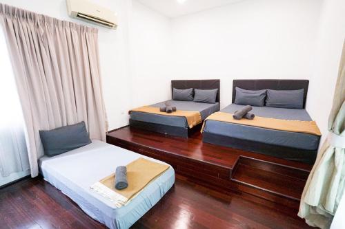 twee bedden in een kamer met houten vloeren bij AU 27pax Bungalow with Pool Table & Swimming Pool in Kuala Lumpur