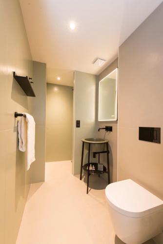 a bathroom with a toilet and a table at L'Anderenis Boutique Hôtel in Andernos-les-Bains