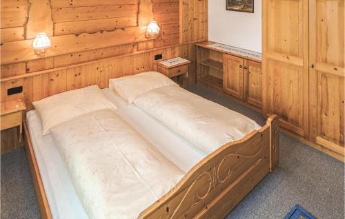 ペットイ・アム・アールベルクにあるNice Apartment In Pettneu Am Arlberg With 2 Bedrooms And Wifiの木製の壁の客室の大型ベッド1台
