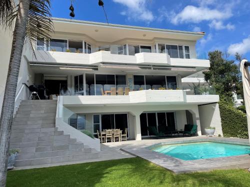 a house with a swimming pool in front of it at Holiday Villa with stunning views near beach. in Plettenberg Bay